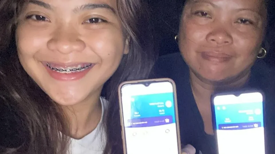 Two app users at night holding up phones showing the Novaluxia home screen — a photo published by the platform itself